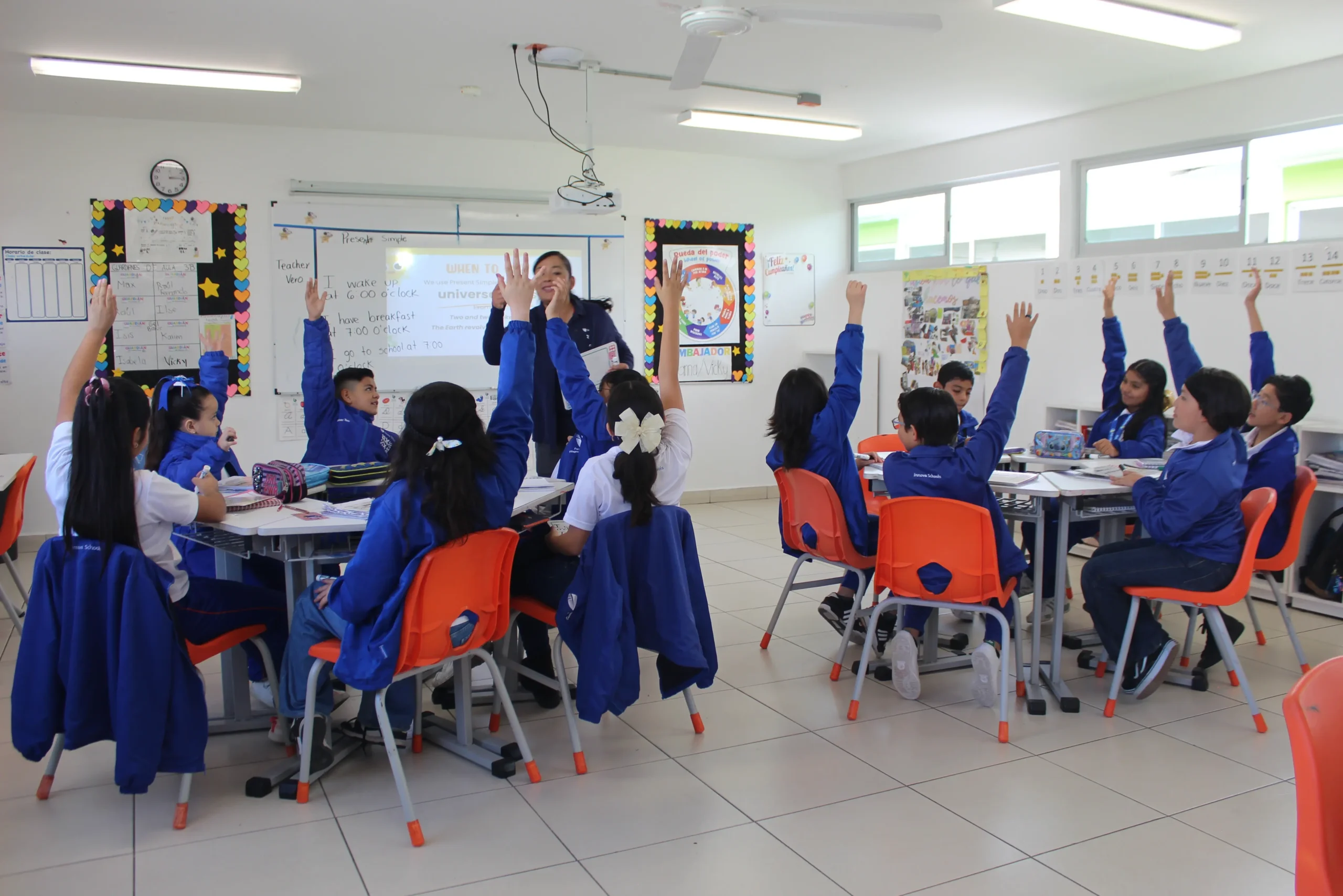 niños alzando la mano en clase de inglés
