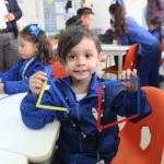 niño de kinder mostrando unas figuras geométricas hechas de popotes
