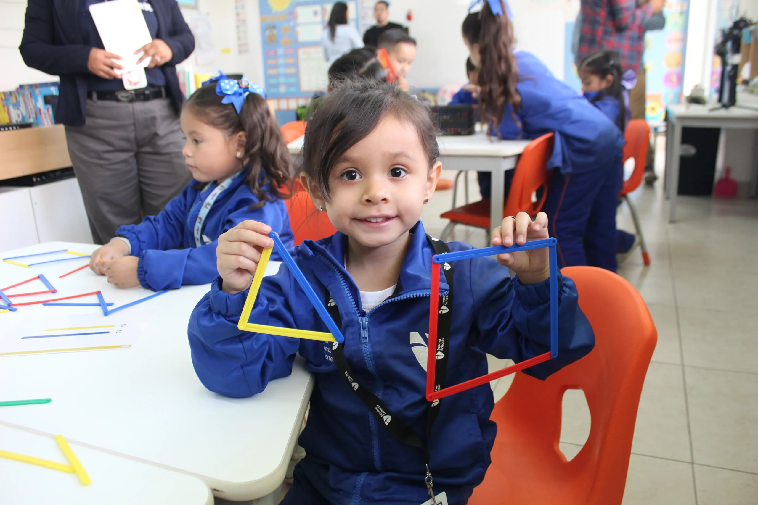 niño de kinder mostrando unas figuras geométricas hechas de popotes
